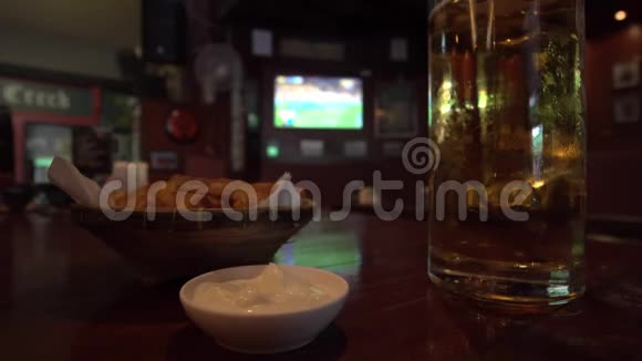 男子在足球比赛电视背景的体育酒吧喝啤酒吃小吃视频的预览图