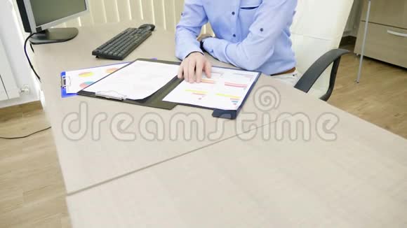 一位雄心勃勃的年轻商人正在他的办公室里工作电脑旁边放着装满图表的文件夹视频的预览图