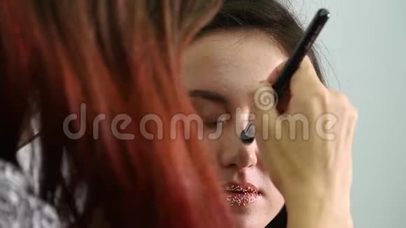 近距离射击专业化妆师将化妆应用在美丽的年轻性感模特的脸上美与美视频的预览图