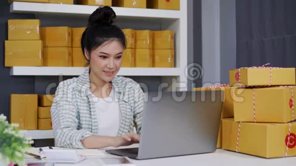 快乐的女人用她的笔记本电脑和快递包裹盒工作视频的预览图