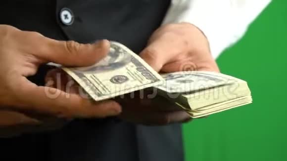 一个穿着商务服的商人的手在赫罗莫基的背景下数着一百美元的钞票视频的预览图