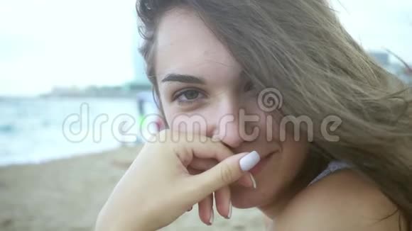 肖像美丽的女孩坐在海滩上迎风飘扬的女人视频的预览图