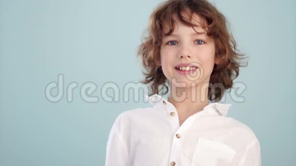 少年身上的白衬衫美丽的白种人微笑的孩子在浅蓝色的背景上童年概念视频的预览图