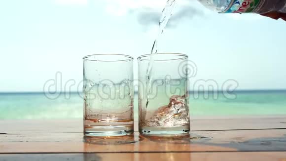 在热带海滩上清澈的水被倒进一个靠海的玻璃杯里3840x2160视频的预览图