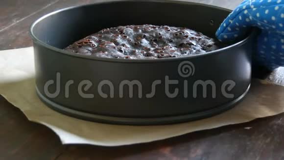 女性手戴蓝色厨房手套桌上放着刚出炉的自制巧克力饼视频的预览图