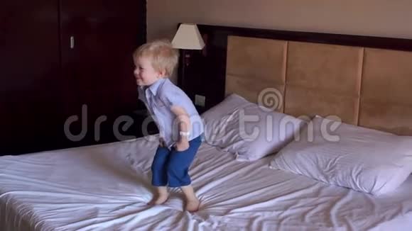 快乐的小男孩在大床上跳跃慢着视频的预览图