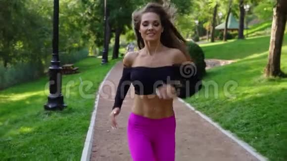 穿着运动胸罩在阳光明媚的城市公园跑步的年轻女子在户外锻炼稳定射击慢动作视频的预览图
