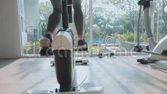 在健身馆里骑着静止的自行车慢动作的特写女性脚视频的预览图