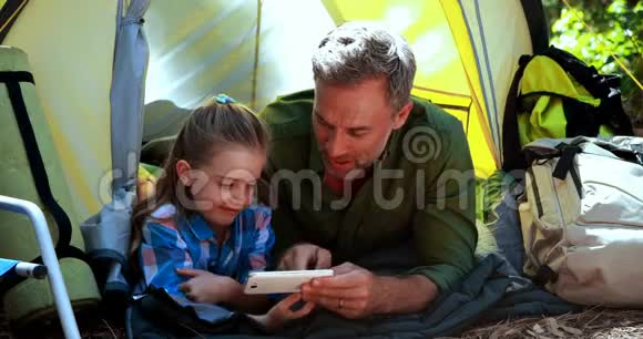 父女在帐篷外用手机视频的预览图