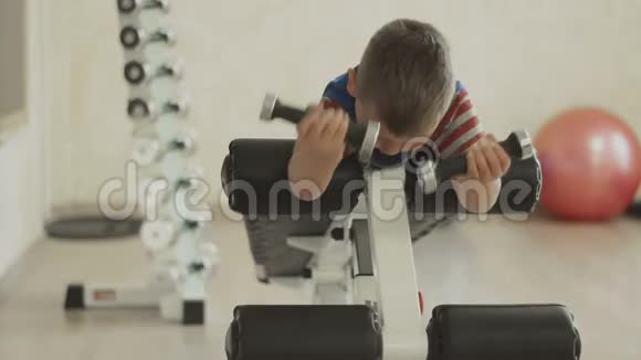 小男孩做肱二头肌重量哑铃运动视频的预览图