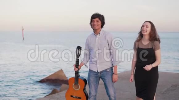 美丽的音乐家夫妇沿着海边的码头散步视频的预览图
