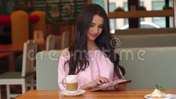 穿着粉色连衣裙的女孩坐在咖啡馆里视频的预览图