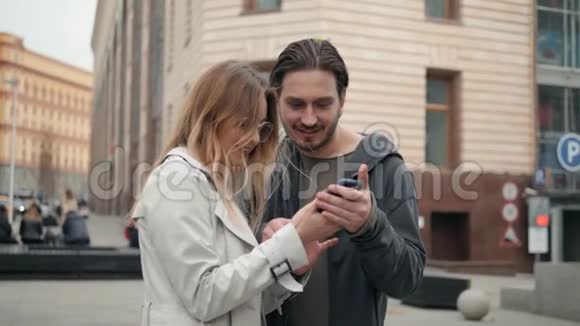 在户外使用手机或平板电脑的情侣男人和女人使用手机电脑导航年轻学生视频的预览图