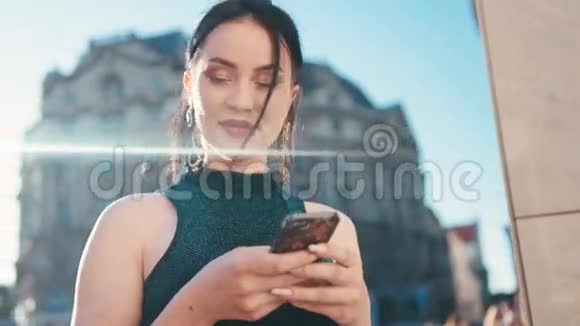 一位年轻漂亮的黑发女人在明亮的阳光下用手机旋转环顾四周高兴地发短信视频的预览图