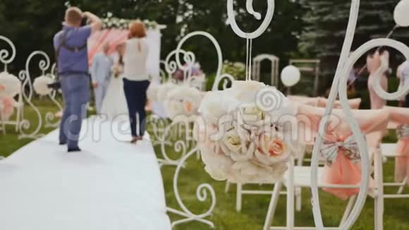 在露天举行节日仪式的婚礼装饰品椅子上的装饰品新郎新娘站在下面视频的预览图