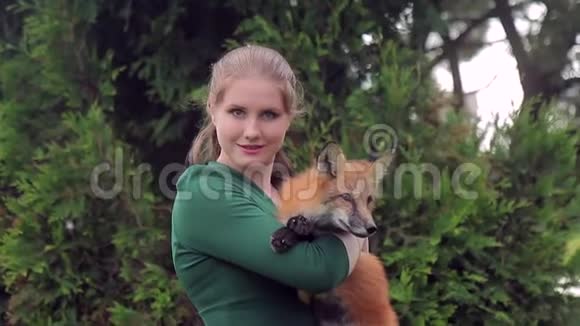 年轻女子抱着狐狸在室外镜头前摆姿势视频的预览图