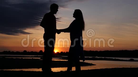 黄昏时分一对虚荣的夫妇在河边拥抱着欣赏的景色高清1920x1080慢动作视频的预览图