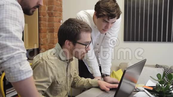 年轻人一起工作讨论他们创造性的创业公司寻找笔记本电脑的显示器商人视频的预览图