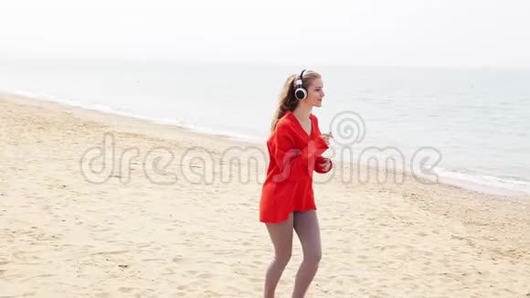 在海边的海滩上女人用大耳机听音乐视频的预览图