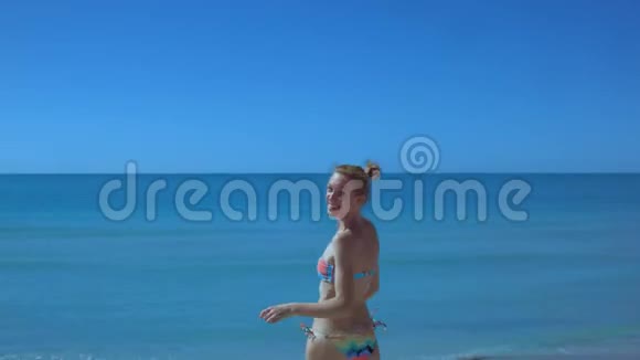 美丽苗条的女孩沿着海边的海滩奔跑奔跑着年轻的女人视频的预览图