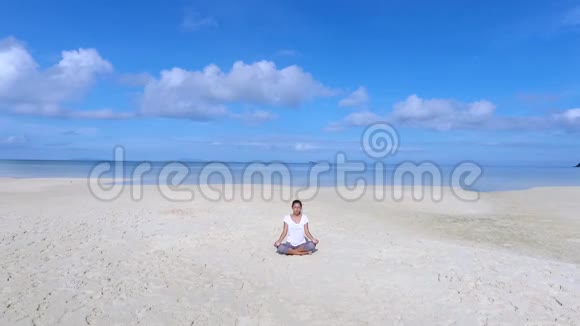 空中瑜伽冥想在美丽的海滩日出年轻冷静美丽的混血女孩坐在沙滩上视频的预览图