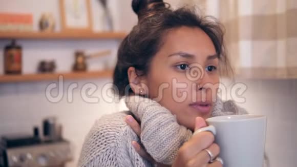 迷人的年轻混合种族妇女在冬季汗水喝热茶从白木在厨房视频的预览图