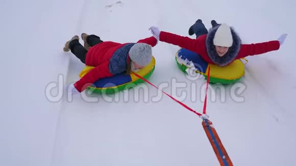 穿红色夹克的女孩在冬天骑着充气雪管穿过雪地扮演超级英雄快乐的女孩视频的预览图