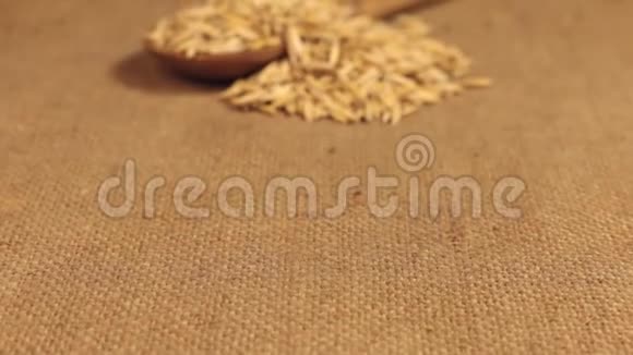 接近一个装满燕麦颗粒的木勺躺在麻布上视频的预览图
