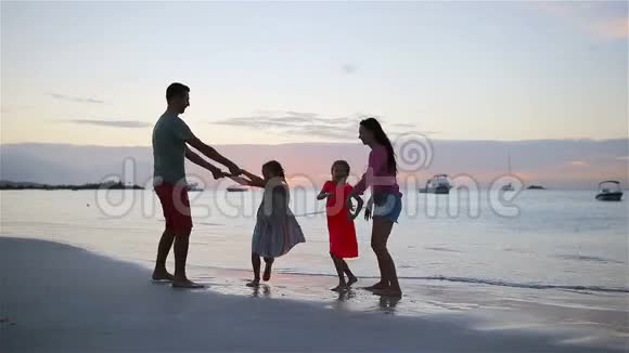 暑假期间在海滩上快乐的美丽家庭四口之家在海滩日落时玩得开心视频的预览图