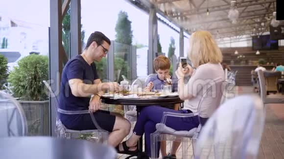 一家人和儿子一起在餐馆的露台上吃饭视频的预览图