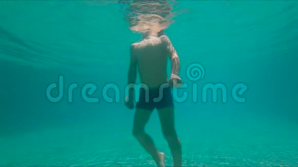 一个可爱的小男孩手里拿着两颗在水下的鹅卵石潜入游泳池动作缓慢视频的预览图