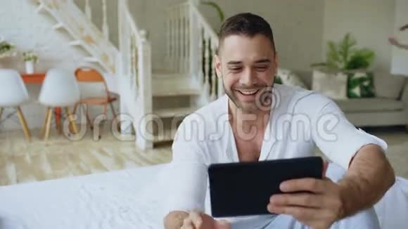 年轻迷人的男人用平板电脑进行视频聊天而他的女孩来拥抱他可爱的一对视频的预览图