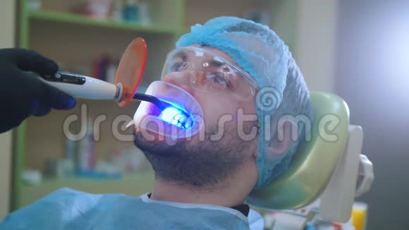 医生和病人在牙科办公室用拉钩用紫外线和橙色保护屏清洁视频的预览图