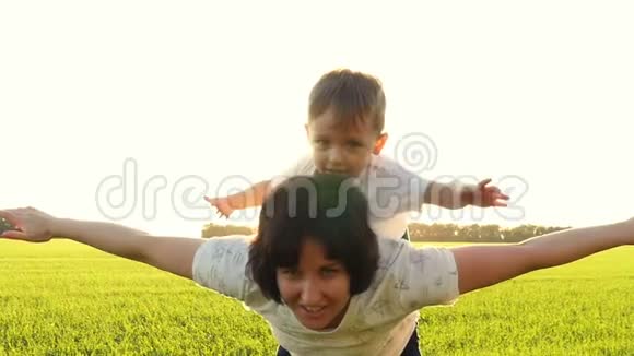 妈妈和孩子用手展示飞机妈妈和她的小儿子在户外玩得很开心妈妈把孩子抱起来视频的预览图
