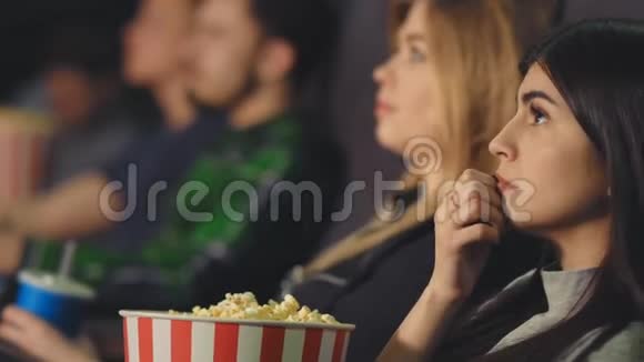 黑发女人在电影院看电影手里拿着爆米花视频的预览图