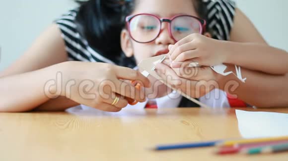 穿着泰国幼儿园学生制服的亚洲小女孩和她的母亲用剪刀剪白纸使家庭变胖视频的预览图