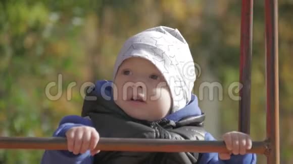 小男孩在公园的儿童操场上摇摆快乐的孩子在户外玩得很开心视频的预览图