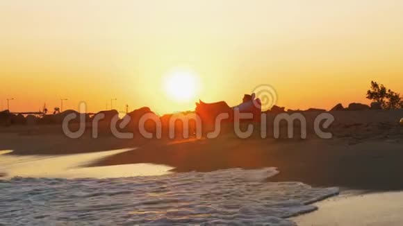 日落时分人们在海滩上的充气日光浴床上放松视频的预览图
