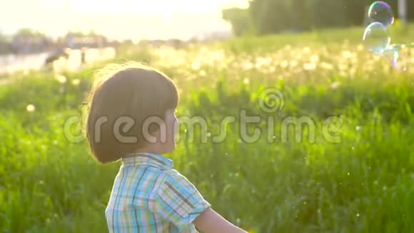 特写照片快乐的小可爱男孩在公园玩肥皂泡小孩子玩父母视频的预览图