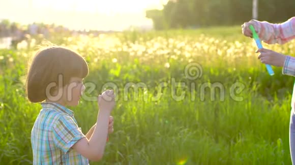 特写快乐小可爱男孩的肖像在公园里玩肥皂泡小孩子在外面玩视频的预览图