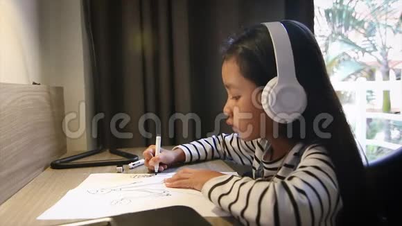 4K亚洲小女孩在桌子上画画听着用广角镜头视频的预览图