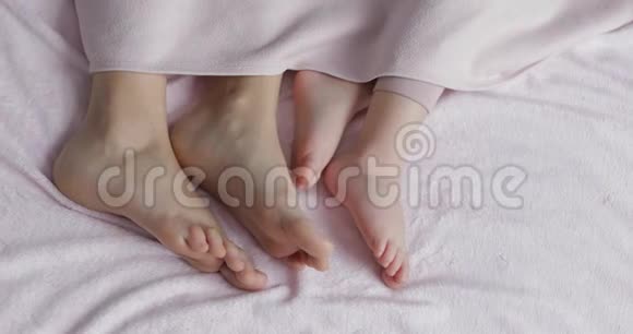 一家人的两条腿躺在被子下面的床上母亲和婴儿视频的预览图