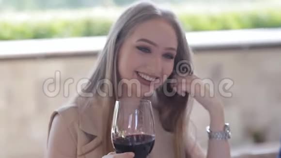 可爱的年轻女子喝着红酒坐在户外的咖啡馆里欣赏着海湾和游艇的美景视频的预览图