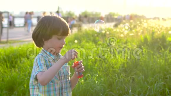 特写快乐小可爱男孩的肖像在公园里玩肥皂泡小孩子在外面玩视频的预览图
