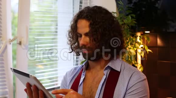 男人在平板电脑上看新闻在厨房里喝咖啡视频的预览图