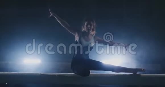 女孩是一名职业运动员在运动中背光和慢动作的横梁上表演体操杂技视频的预览图