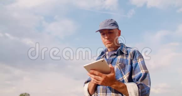农民在农场使用数字平板电脑对抗蓝天和云彩视频的预览图