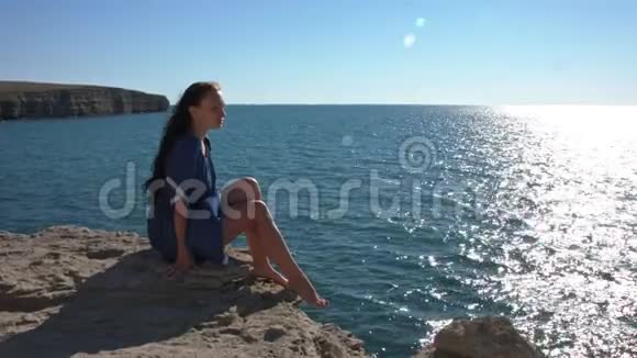女孩坐在悬崖边上看着大海视频的预览图