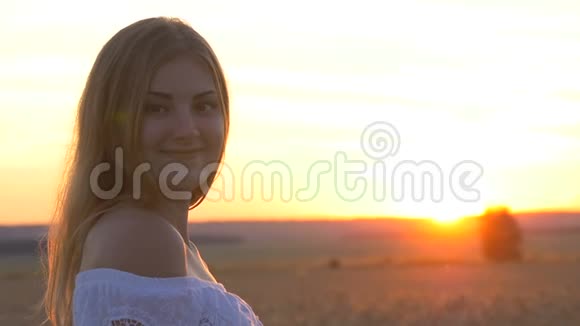 太阳落山时麦田里一个年轻漂亮女孩的脸我脸上洋溢着快乐的表情和微笑视频的预览图