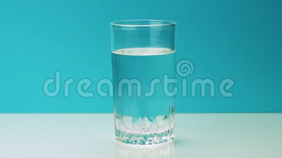 一片泡腾的黄色止痛片落入玻璃杯中将慢镜头的阿司匹林溶解在水中视频的预览图